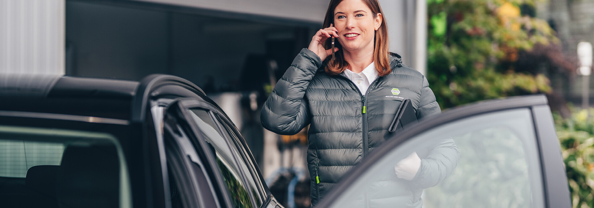 Außendienstmitarbeiterin telefoniert am Auto